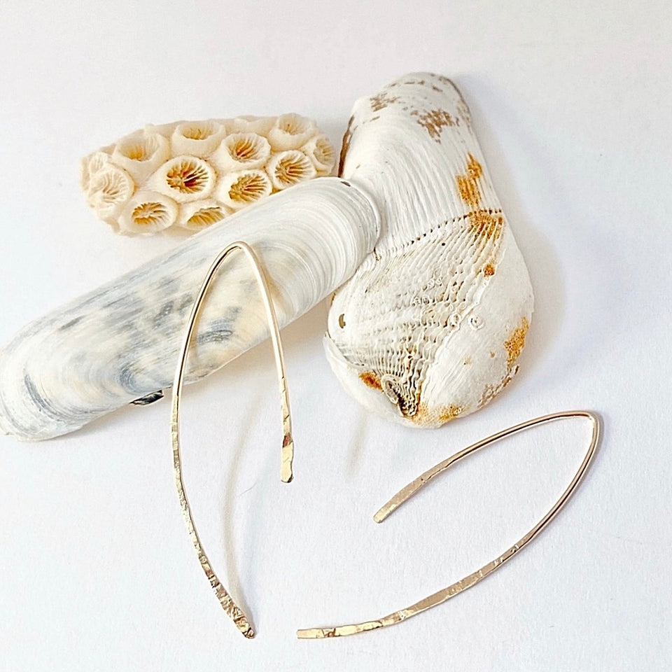 Gold hoop earrings with natural seashells on a white background